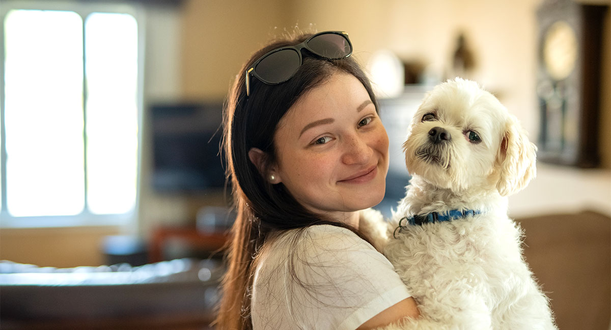 Chanelle tenant son chien blanc, Everest, dans son salon.